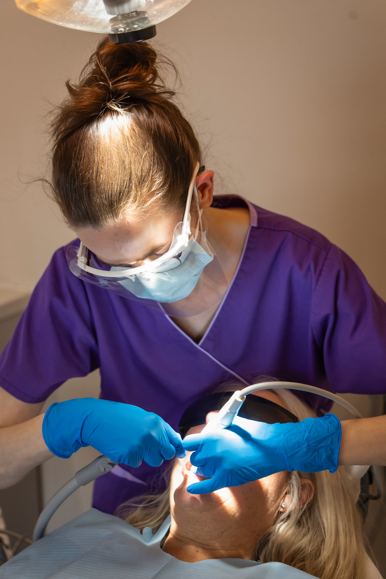Dental hygienist performing a professional cleaning on a patient in the surgery