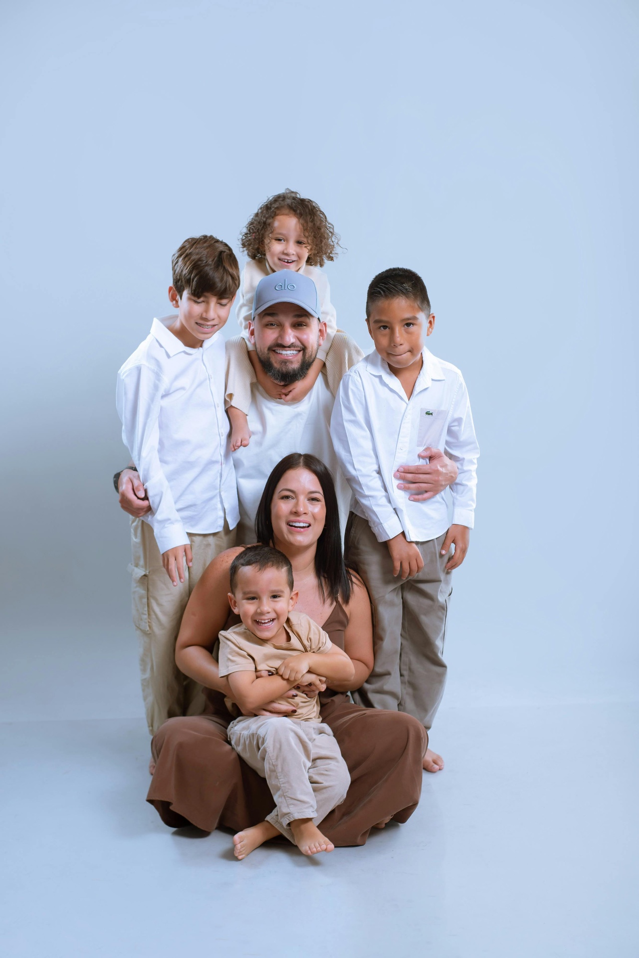 Family with four children smiling together in a studio portrait