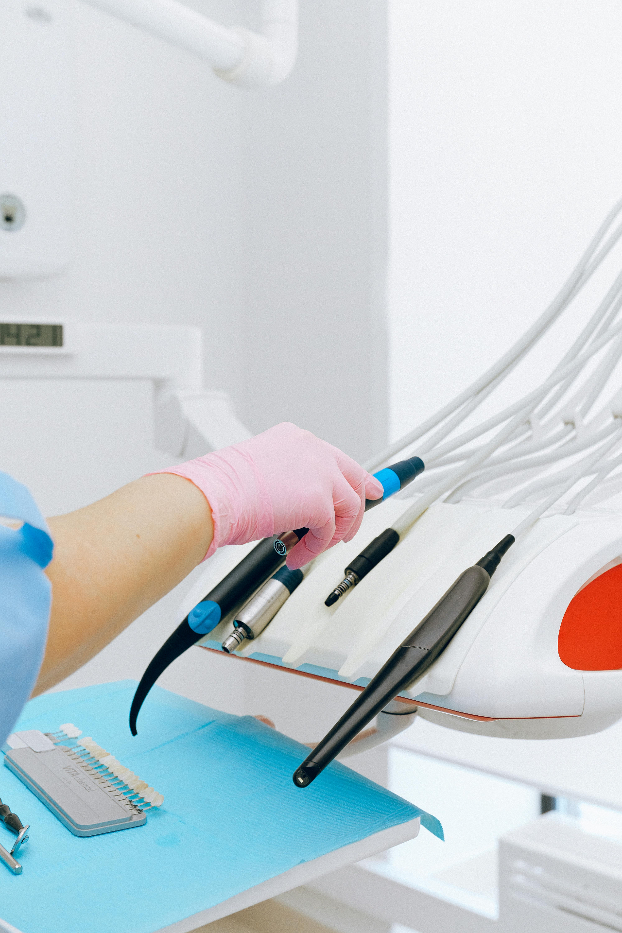 Dental clinician selecting a laser handpiece from a tray of modern surgery instruments